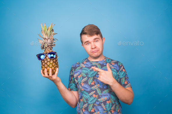 Funny man hold pineapple with sunglasses on blue background