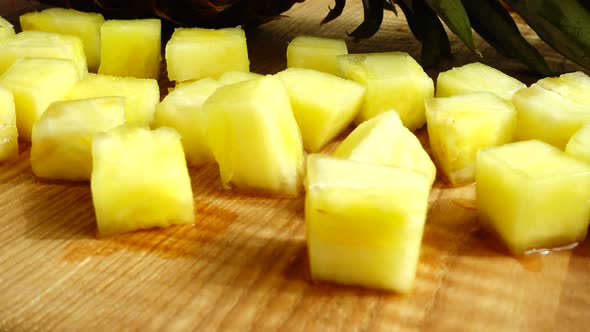 Pieces of pineapple on a cutting wooden board. alt
