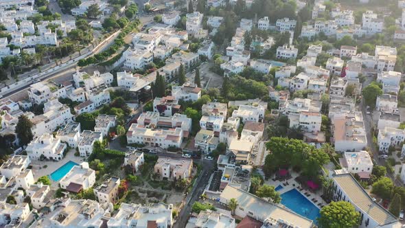 Aerial street view of white villas in Bodrum Turkey as the sun sets over the homes during a sunny su alt
