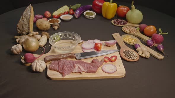 Fresh Meats, Vegetables And Spices Are Laid Out On A Black Table alt