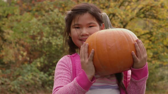 Young girl in Fall holding pumpkin