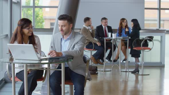 Businesspeople using laptop computer in office lobby