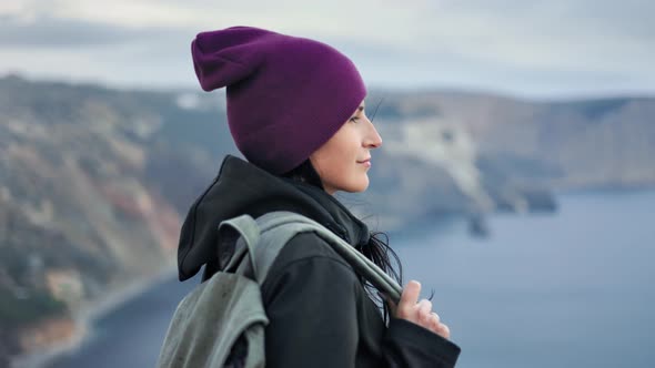 Closeup Smiling Hipster Backpacker Woman Admiring Nature Panorama with Cliff and Sea Top Mountain alt