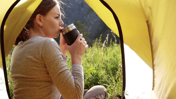 Girl Is Drinking Tea From a Mug of Thermos on the Background of Mountains alt