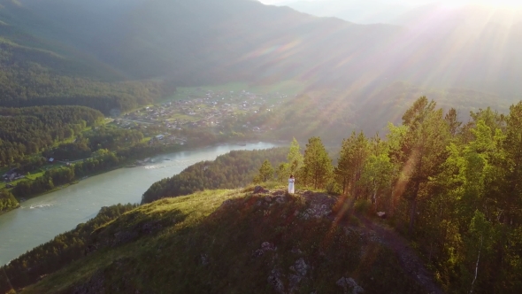 A Girl in a White Dress Is Standing on a Mountain a Beautiful View From Above alt