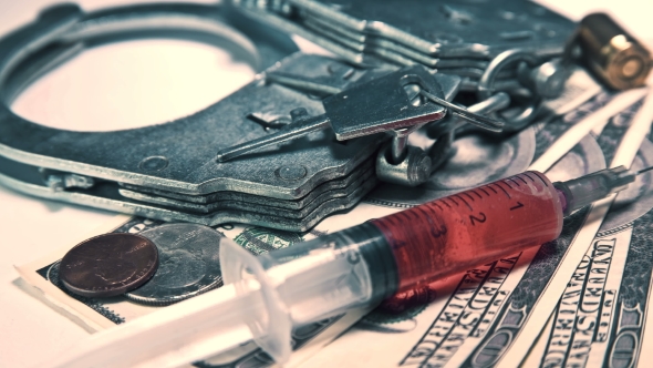 Handcuffs with Keys, Money and a Syringe with Drugs alt