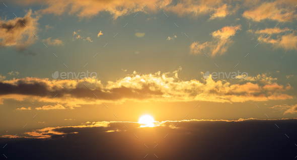 Beautiful sunset on sky. Gold sun lightens the clouds. The sun is in the middle.