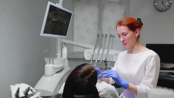 Female Doctor in Blue Gloves and a White Coat Approaches To the Chair of the Patient and Using X-ray alt