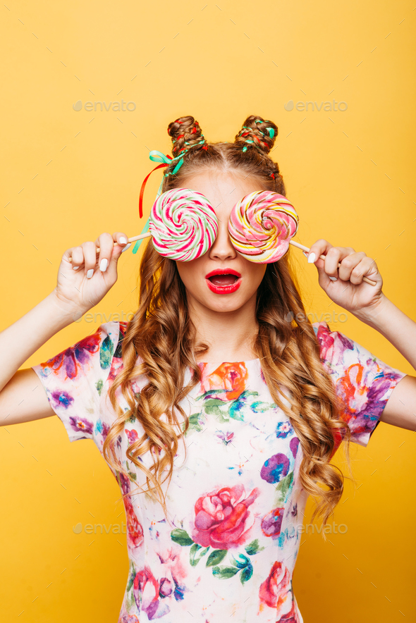 Young girl on the yellow background holding sweets - Stock Photo - Images
