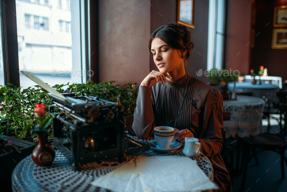 Happy young woman sits by the table in cafe - Stock Photo - Images