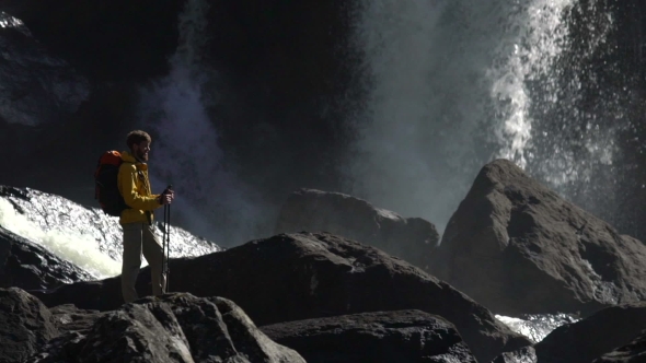 A Male Hiker Watches a Huge Waterfall in .