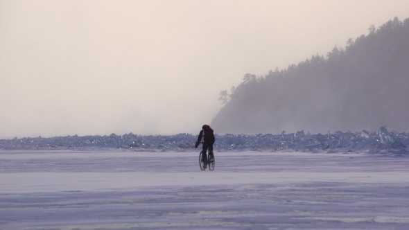 a Man Riding a Bicycle Across a Frozen Lake