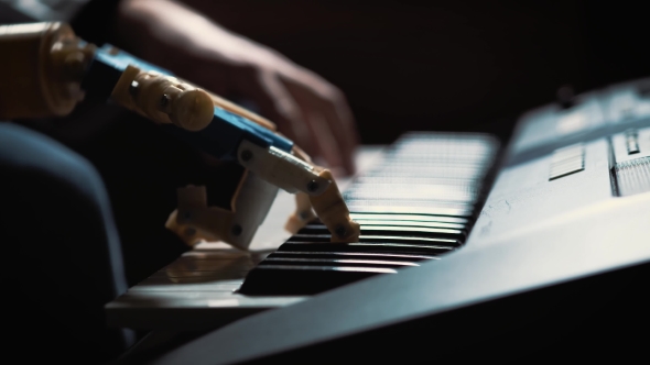 Man Musician Pianist with a Prosthetic Hand Playing the Piano. He Plays with Two Hands, a Robot Hand