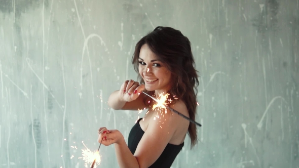 Cheerful Girl Holding in the Hands of Sparklers and Laughing. the Young Woman at the Party