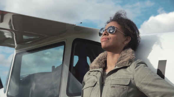 Attractive Woman Pilot Resting Against Her Plane alt