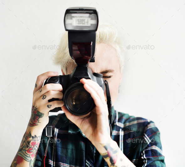 Casual blonde woman with tattoo holding camera taking a snap sho