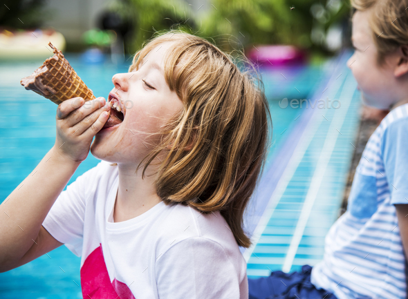 Closeup of caucasian girl eating ice cream by the pool