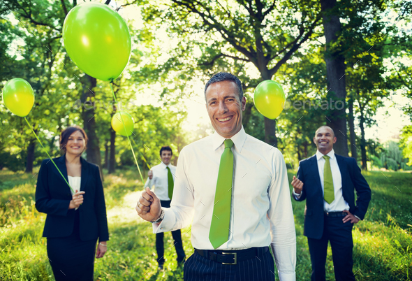Group of business people holding balloons in the forest.