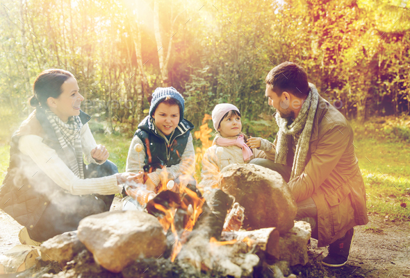 happy family roasting marshmallow over campfire