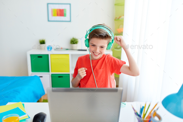 boy in headphones playing video game on laptop - Stock Photo - Images
