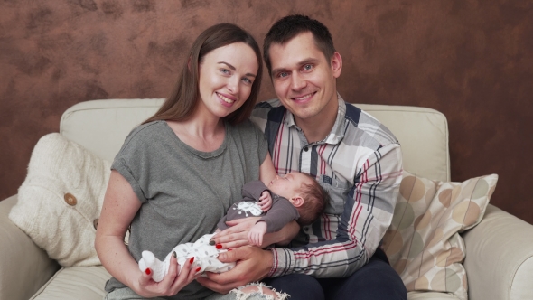 Happy Family with Newborn Baby in Hands at Home