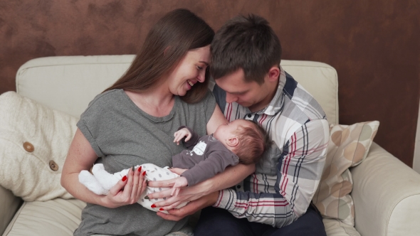 Happy Family with Newborn Baby on Sofa at Home