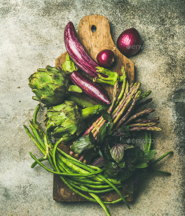 Flat-lay of green and purple vegetables on board, grey background - Stock Photo - Images