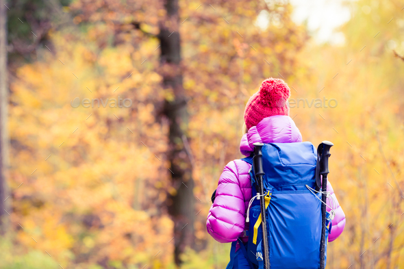 Hiking woman with backpack looking at inspirational autumn golde