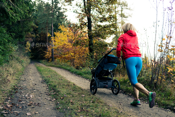 Running mother with stroller enjoying motherhood at autumn sunse