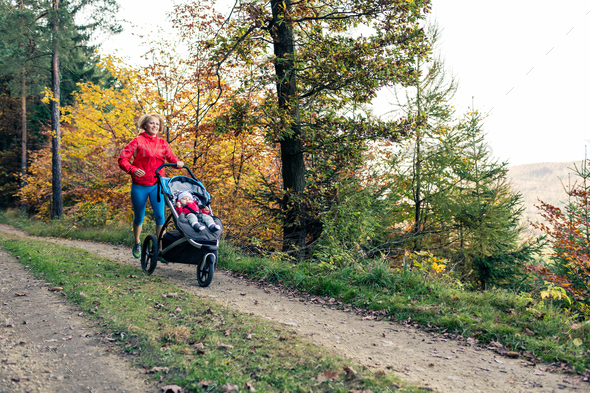 Running mother with stroller enjoying motherhood at autumn sunse - Stock Photo - Images