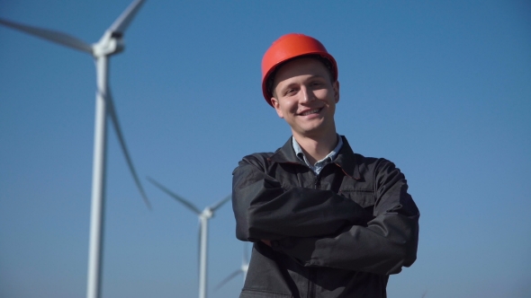 Smiling Engineer Standing Against Wind Farm alt