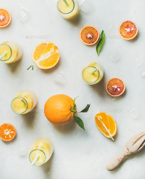 Healthy yellow smoothie with citrus fruit, ginger, ice in bottles - Stock Photo - Images
