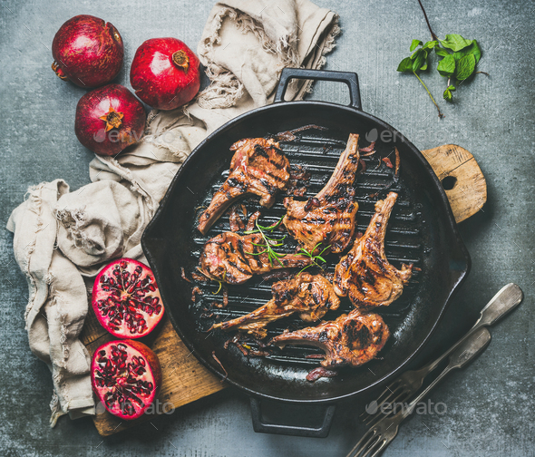 Grilled lamb meat chops served with fresh pomegranates, grey background - Stock Photo - Images