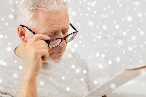 close up of old man in glasses reading newspaper