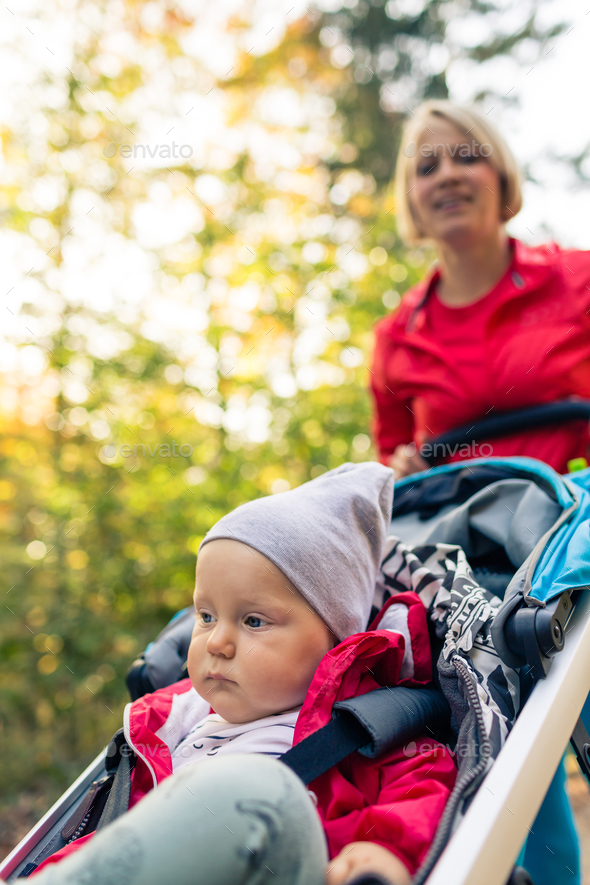 Running mother with stroller enjoying motherhood at autumn sunse