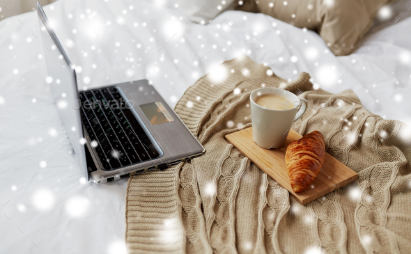 laptop, coffee and croissant on bed at cozy home