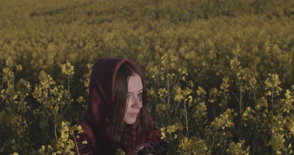 Girl in Hood Hiding in Yellow Field Making Photos on Professional Camera Outdoors Handheld Device