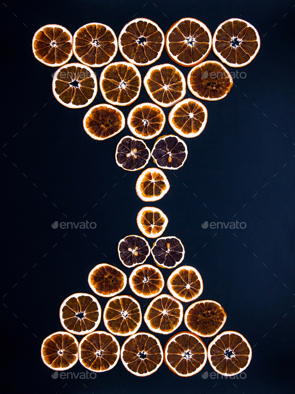 Hourglass made from dried orange slices on black background