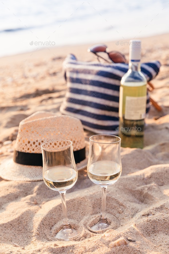 Glasses of the white wine on the sunset beach, picnic theme