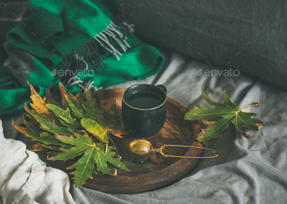 Black mug of tea with sieve and leaves on tray - Stock Photo - Images