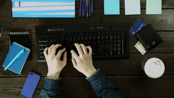 Man Types on a Computer Keyboard on His Desk
