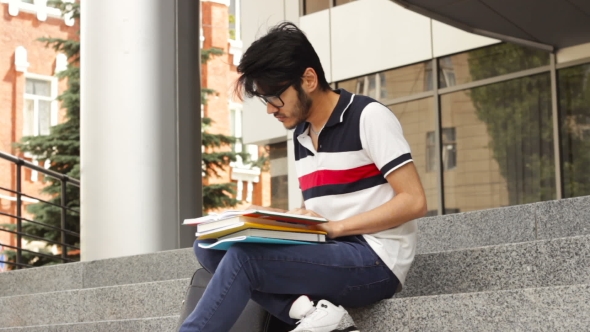 Adult Male Asian Student Sitting on Stairs and Reading Book