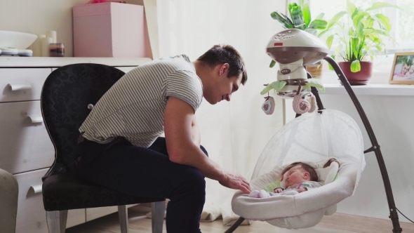 Father Rocking the Cradle with Baby at Home