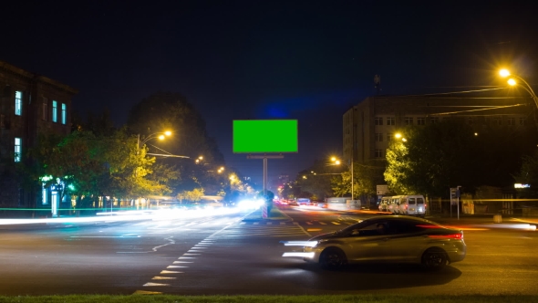 A Billboard with a Green Screen on a Background of City Traffic with Long Exposure. . The Camera Is