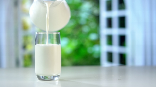 Pouring Fresh Milk From the Jug on Table