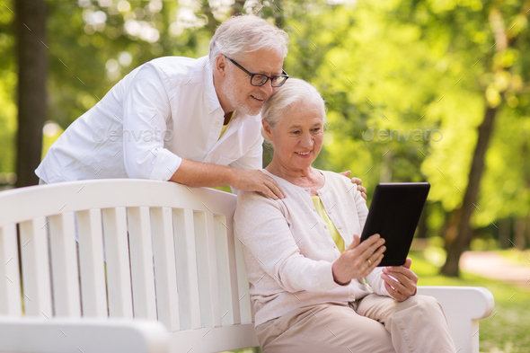 happy senior couple with tablet pc at summer park