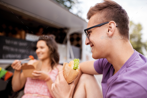 happy man eating hamburger at food truck
