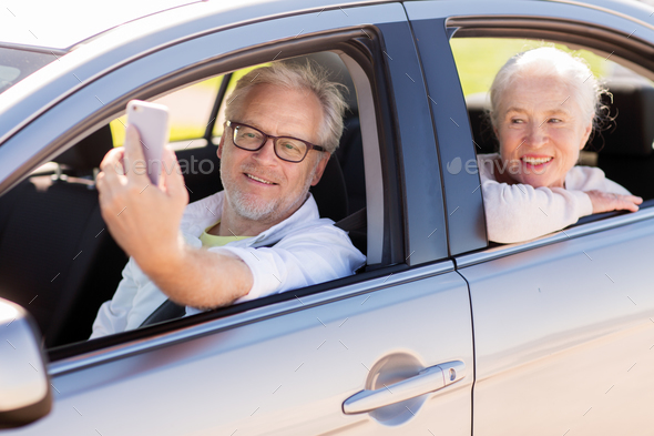 senior couple in car taking smartphone selfie