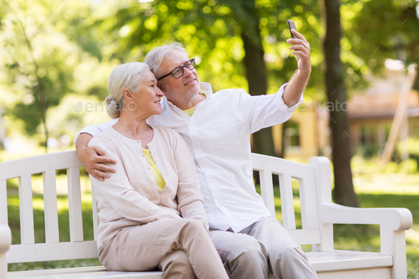 senior couple taking selfie by smartphone at park