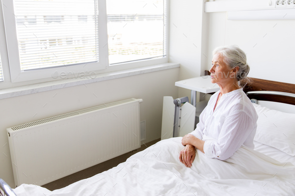 sad senior woman sitting on bed at hospital ward